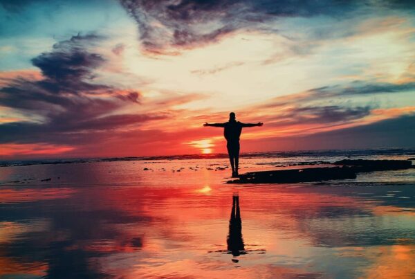 man on the beach with arms out, healing